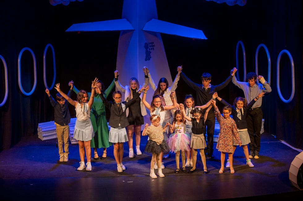 group of children and teens on stage celebrating a performance