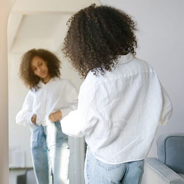 African american girl choosing clothes to wear in front of mirror in i the living room cute african american girl choosing clothes to wear in front of mirror in i the living room. morning wake up concept
