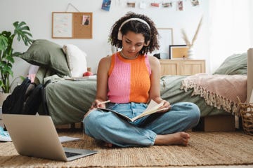 teenage girl wearing wireless headphones doing homework at home