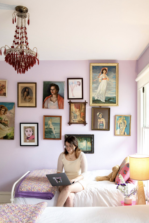 pink wall with gallery wall art and girl sitting on bed