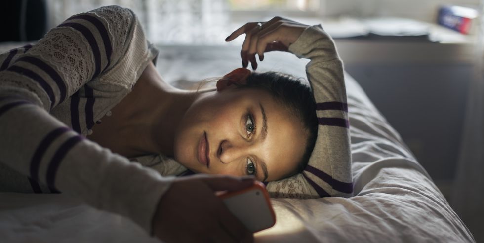 teen girl lying on bed using smartphone