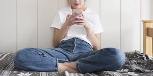 teen girl with phone sitting on bed