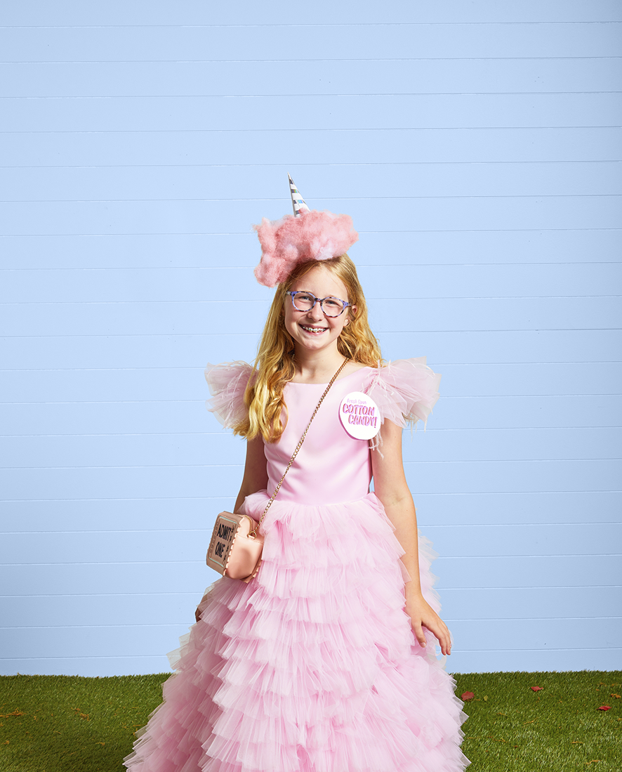 a girl dressed in a long puffy pink dress with a poof of pink cotton on her head to resemble cotton candy