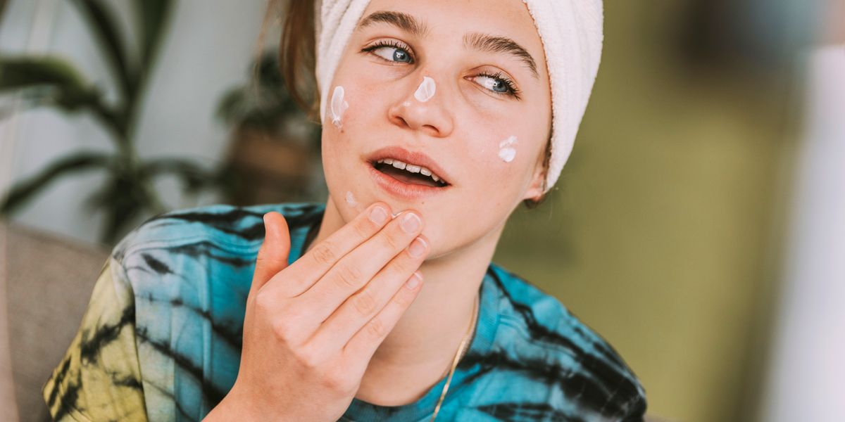 teenager applying skincare to face
