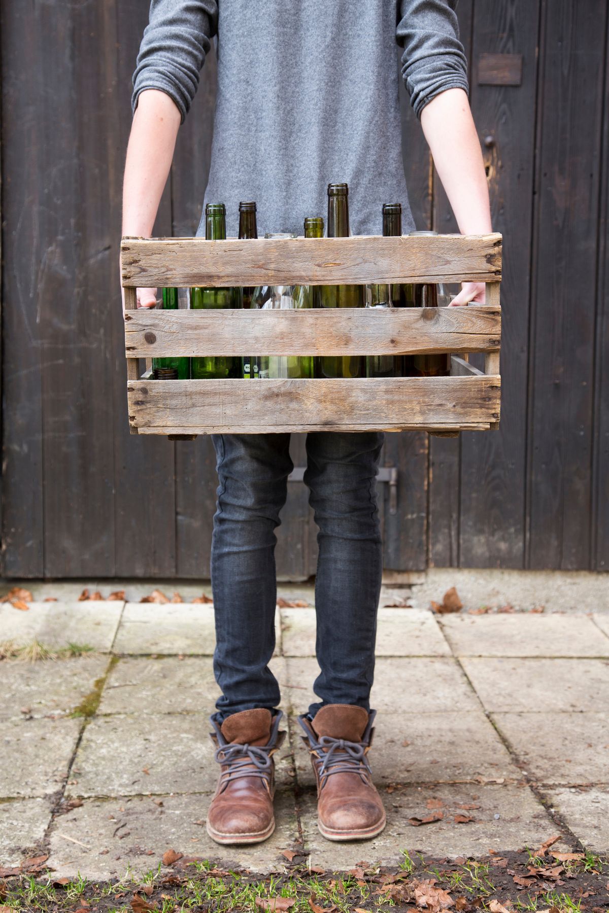 teenage boy carrying empty bottles in wooden crate