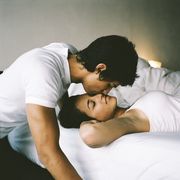Teenage boy (16-18) kissing girl sleeping in bed