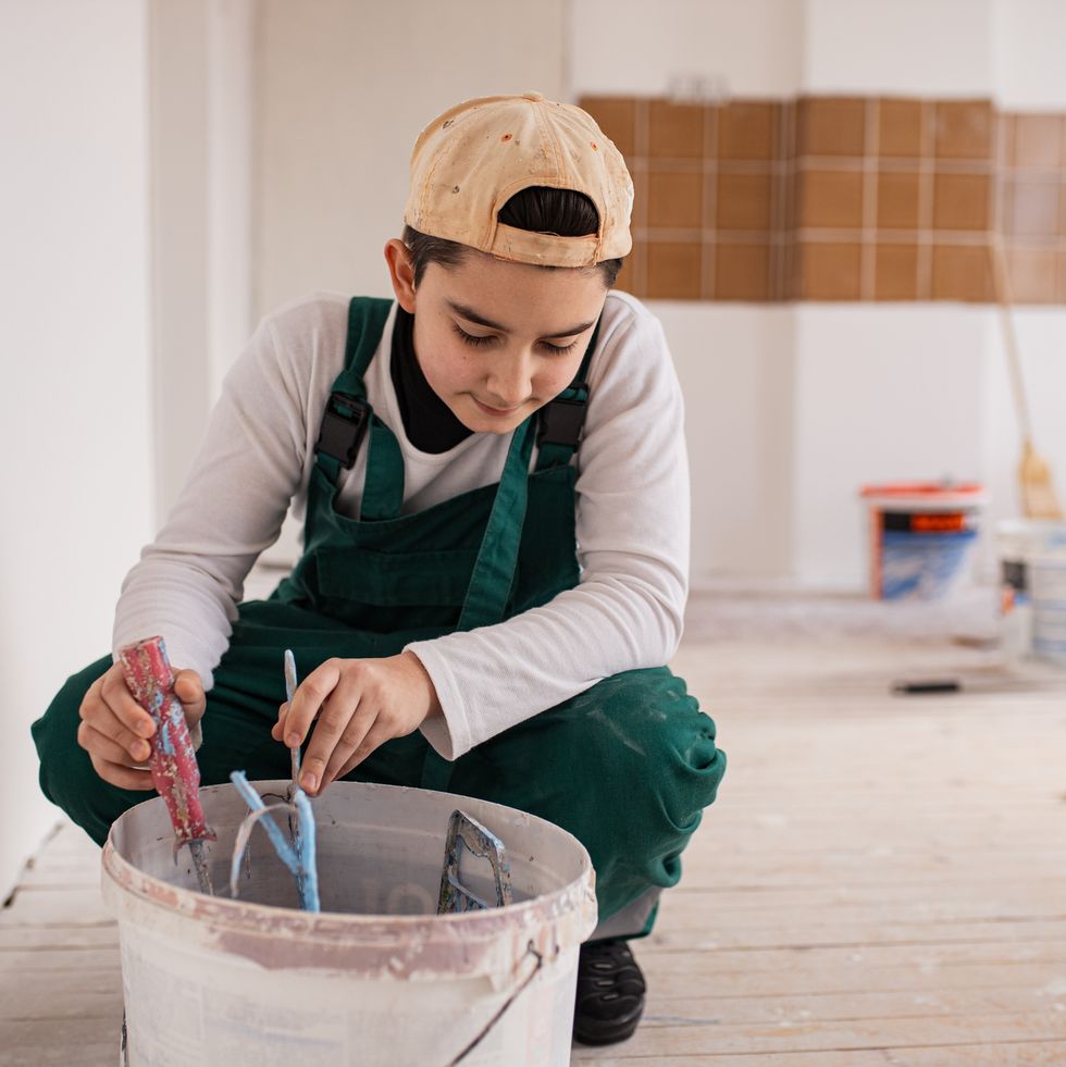 teenage boy mixing wall paint in the bucket