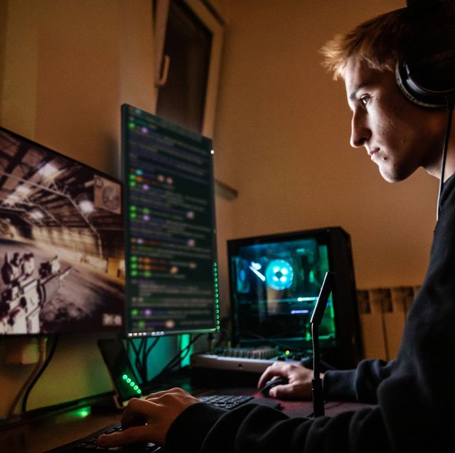 teenage boy playing multiplayer games on desktop pc in his dark room   stock photo