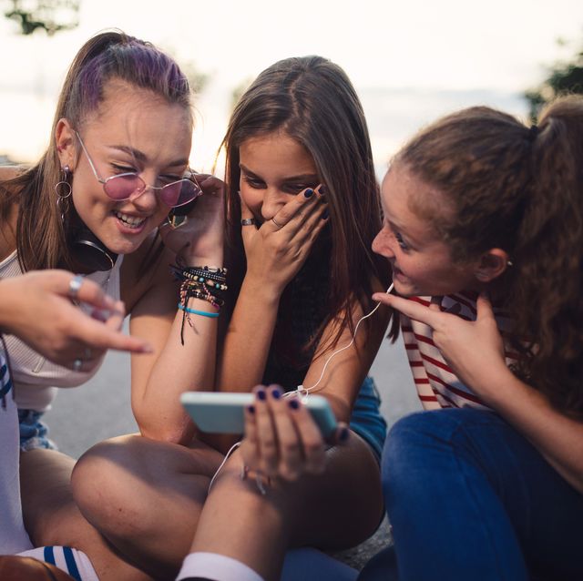 teenage female friends looking something fun on mobile phone
