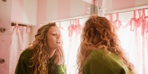 teenage girl checking skin in bathroom mirror
