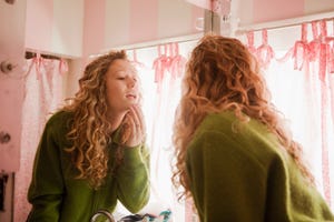 teenage girl checking skin in bathroom mirror