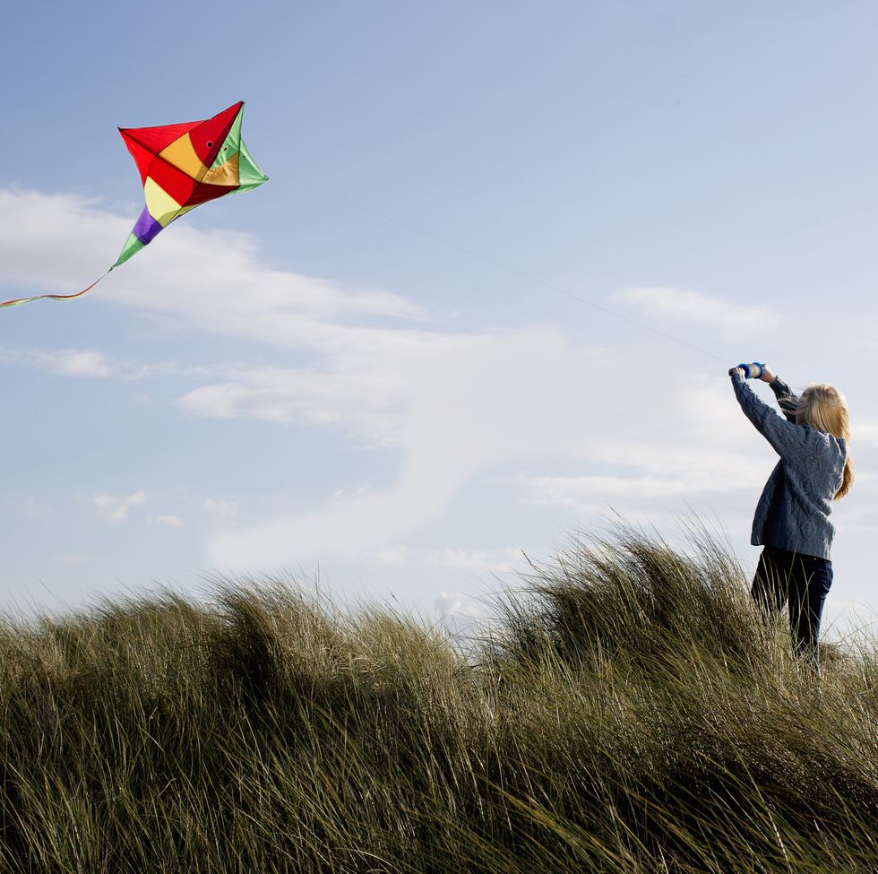 teenage girl flying a kite on the beach