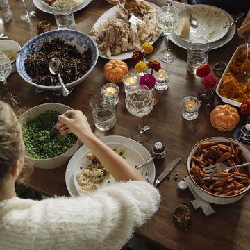 teenage girl having food while sitting at dining table during thanksgiving