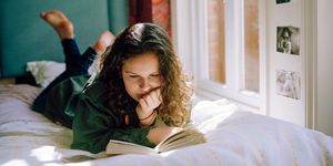 chica joven leyendo un libro tumbada en la cama