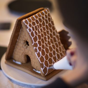 piping icing onto a gingerbread house