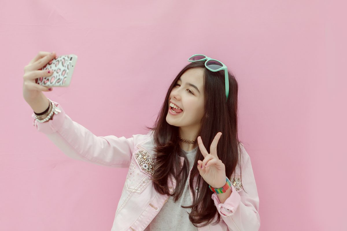 Teenage girl taking picture of herself with smartphone