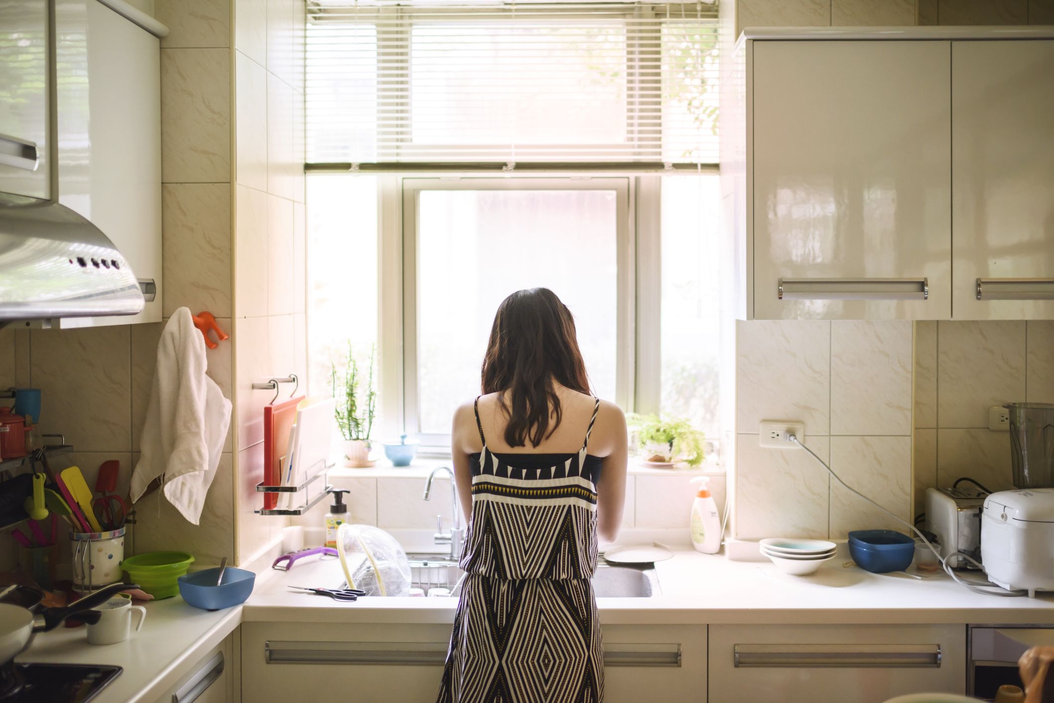 teenage girl washing dishes in kitchen