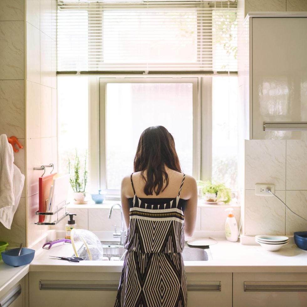 teenage girl washing dishes in kitchen