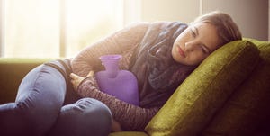 Teenage girl with hot water bottle on sofa