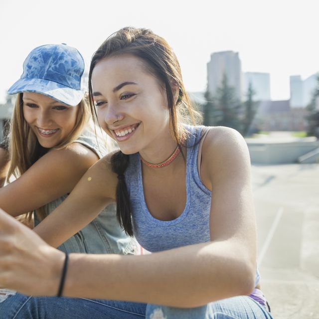 Teenage girls with cell phone at skateboard park