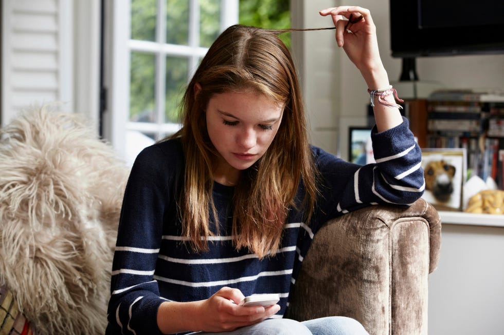 Ragazza che guarda il telefono mentre si arriccia i capelli