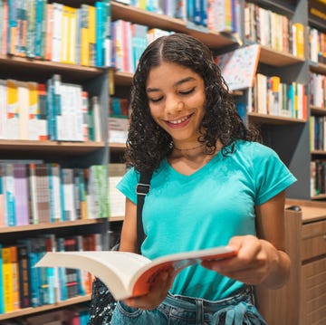 teenager girl reading book in library