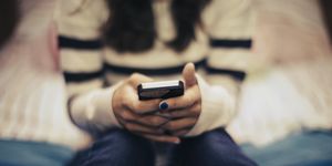 teenager using social media on phone in bedroom