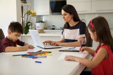 mujer teletrabajando con sus hijos al lado
