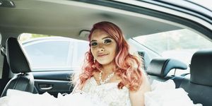 Smiling young woman in quinceanera gown sitting in back seat of car