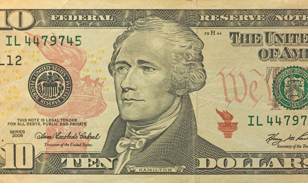 partial view of a paper ten dollar bill with a portrait of alexander hamilton looking left