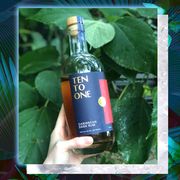 danielle holding bottle of ten to one rum with leaves in background