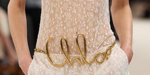 a person wearing a white dress with gold text on it
