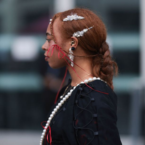 london, england september 17 a fashion week guest is seen wearing a complete simone rocha look, consitinng of an earring with gemstone ornaments and sr logo covered in rhinestones another smaler earring with peals and transparent ornaments the matching hair clips a black dress with laced up details, puffy sleeves, round high neckline, mesh parts and several red bows a creme white egg shaped bag with pearl strap during london fashion week september 2023 before the simone rocha show on september 17, 2023 in london, england photo by jeremy moellergetty images