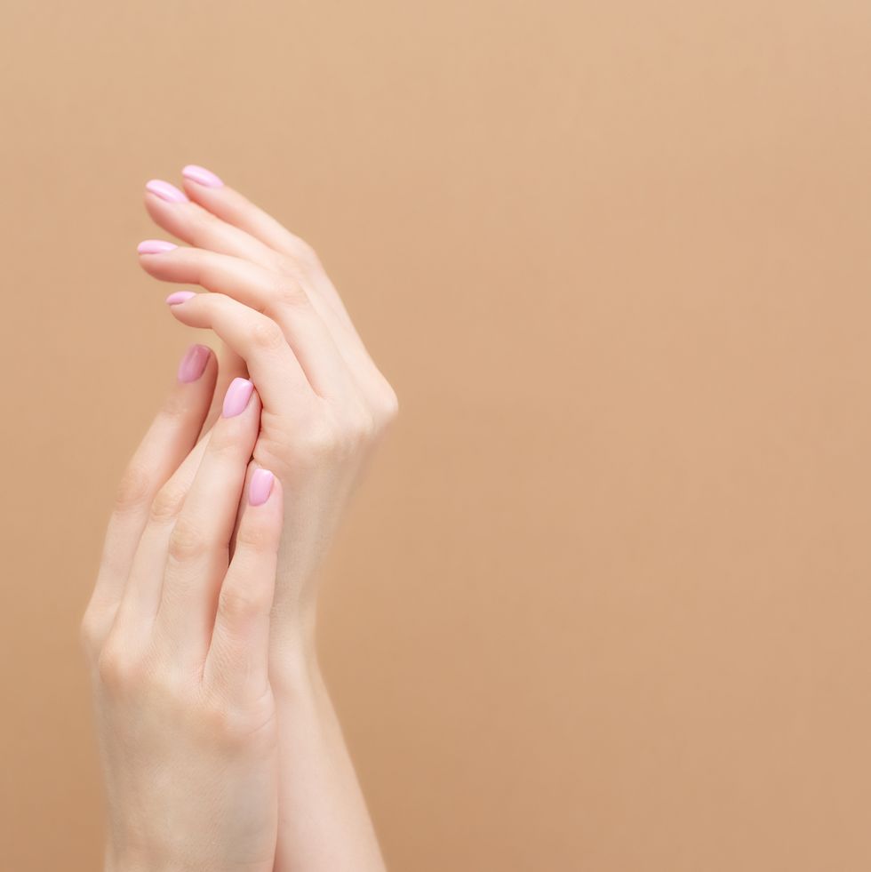 tender hands with perfect blue and pink manicure on trendy pastel pink background place for text