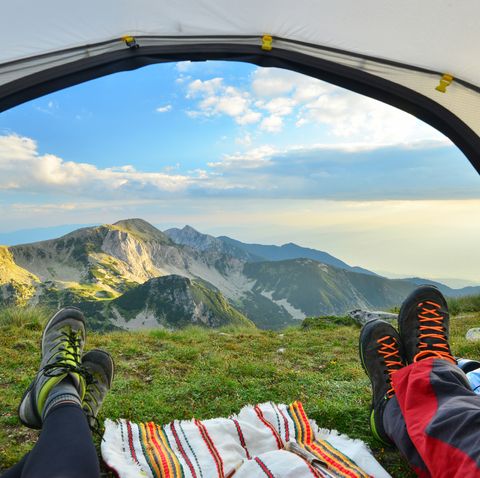 Tent view of mountain range with hiking boot in the foreground