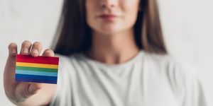 close up shot of young transgender man holding card with pride flag on white