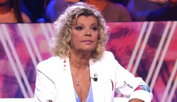 a person seated in front of an audience with a colorful background