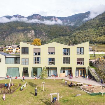 una scuola col il parco giochi attrezzato con sfondo le montagne