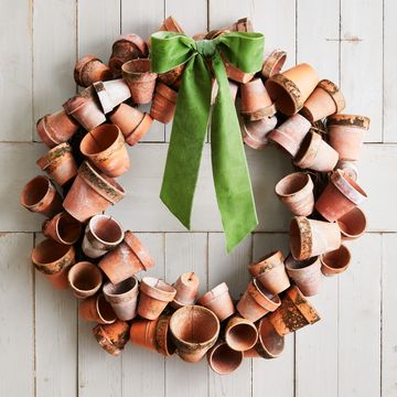 a wreath made from crusty terra cotta pots hung on a white barn door with a green bow attached to the top of the wreath