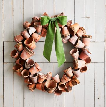 a wreath made from crusty terra cotta pots hung on a white barn door with a green bow attached to the top of the wreath
