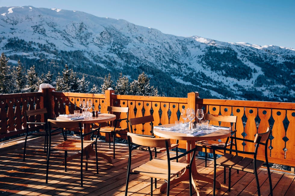 a deck with tables and chairs on it with mountains in the background