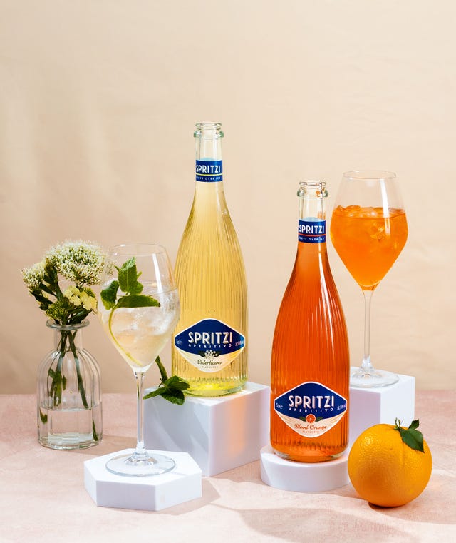 Assorted Spritzi aperitifs and a fresh orange on a pastel background