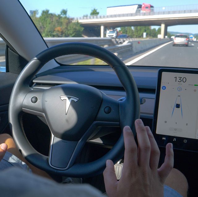 tesla car, slovenia, april 2020 close up unrecognizable man tentatively lets go of steering wheel of a tesla after setting autonomous vehicle on auto pilot man gives control to self steering car