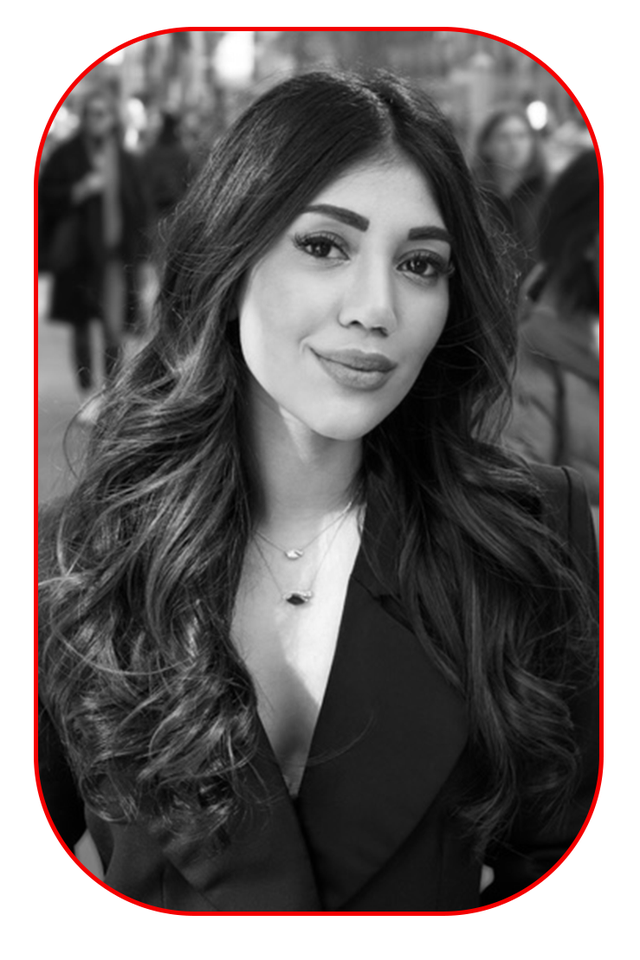 a woman with long wavy hair wearing a black jacket and necklaces