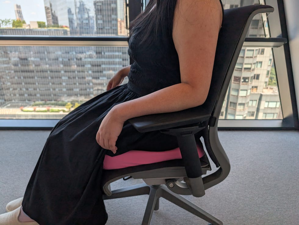 a person sitting on a pink seat cushion on an office chair