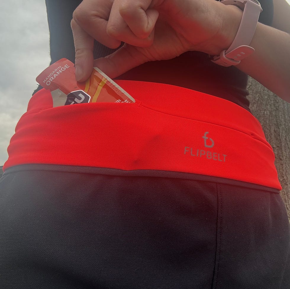Testing the flipbelt a woman pulling out an energy gel of a pocket on the flipbelt running belt