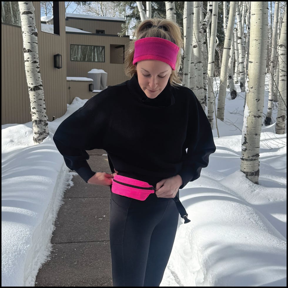 person wearing a black sweater and leggings accessorized with a pink headband and waist pack