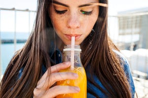 vrouw drinkt sinaasappelsap met een rietje