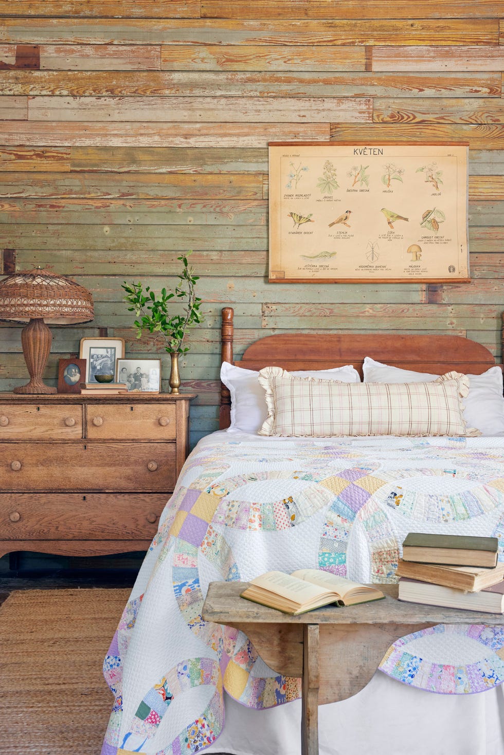 guest bedroom with exposed wood walls and a colorful wedding ring quilt at the end of the bed