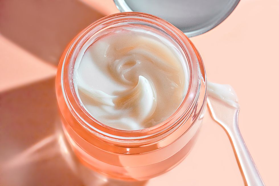 texture of cosmetic product in glass jar skincare face cream, refreshing hydration water cream or hand cream in natural pastel pink beige peach fuzz color of the year 2024 on white colour background with shadow